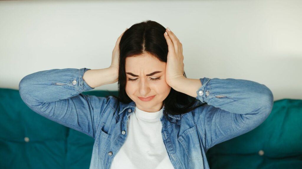 A woman covers her ears because of popping noise in air ducts